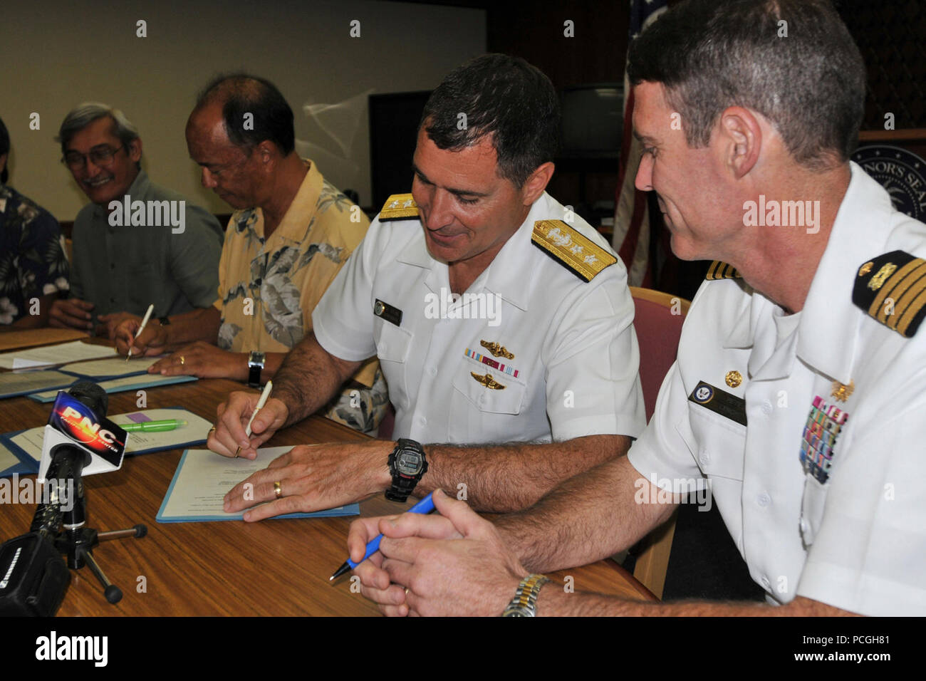 Adm arrière. Paul Bushong, centre, commandant de la région Marianas, signe un protocole d'entente avec la Commission de synthèse sur les services publics, Guam Waterworks Authority et d'électricité de Guam à la Ricardo J. Bordallo complexe du gouverneur à Hagatna, Guam. La Marine américaine est d'accord de collaborer sur des solutions pour améliorer les services publics à Guam en vue de la réinstallation à partir de la Marine l'Okinawa, Japon. Banque D'Images