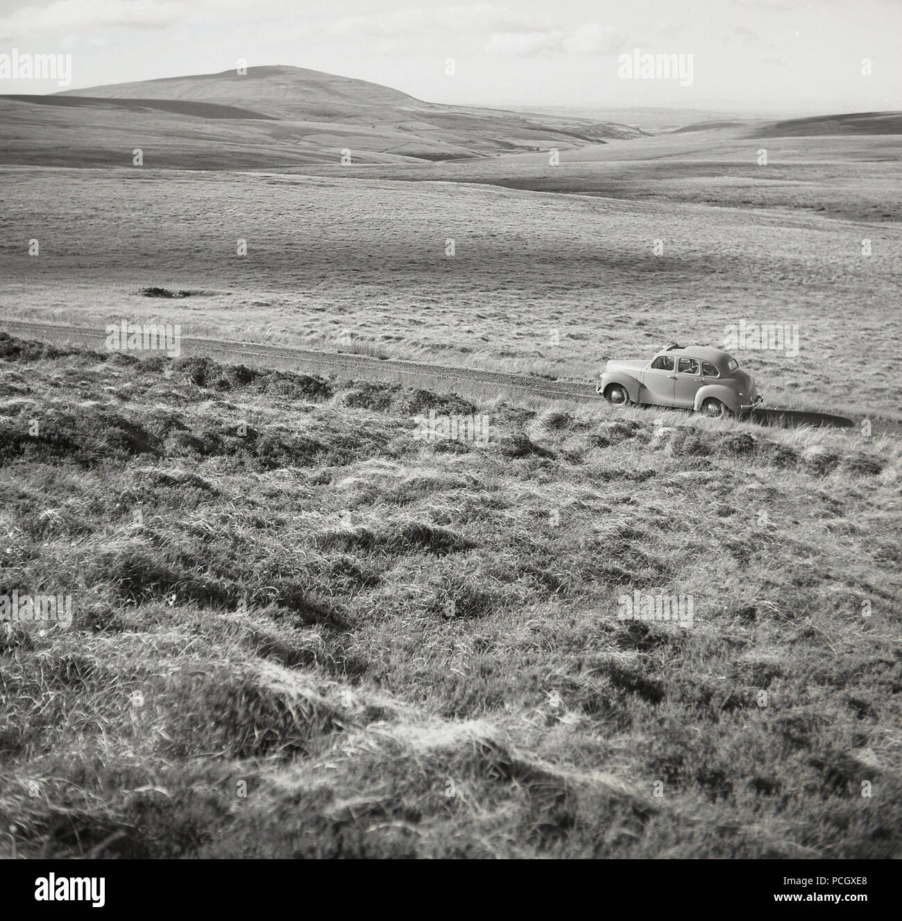 Années 1950, historiques, une voiture de l'époque sur une route secondaire en Co. Antrim...visiter la côte de causeway en Co. d'Antrim, en Irlande du Nord, une zone de côte préservée et glens et une beauté naturelle exceptionnelle. Banque D'Images