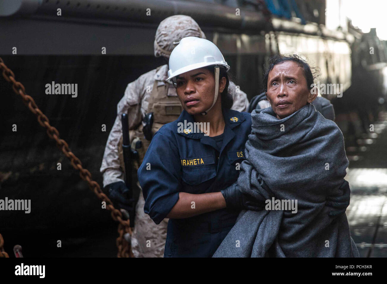 Détroit de Makassar (10 juin 2015) Un marin prend une femme de personnel médical à bord du navire de débarquement quai amphibie USS Rushmore (LSD 47). Rushmore a secouru 65 personnes d'un naufrage de plaisance dans l'océan pacifique entre les îles indonésiennes de Kalimantan et Sulawesi. Une fois à bord, les individus ont été secourus a fourni de la nourriture et des soins médicaux par les Marines et les marins de la 15e unité expéditionnaire de marines et de l'Essex groupe amphibie. Banque D'Images