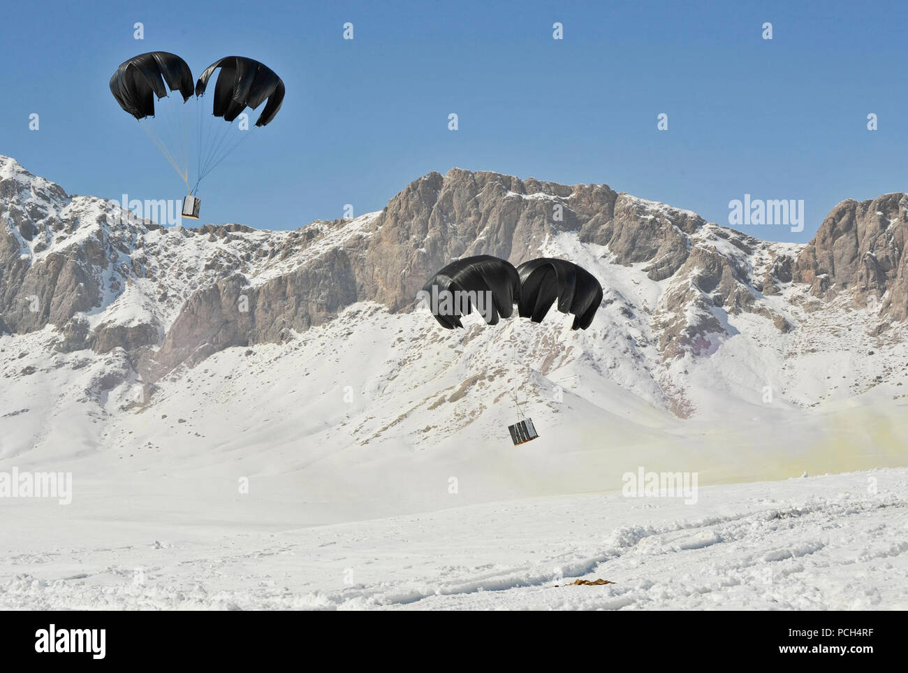 Palettes de fournitures passé d'une M-28 avion camionneur tombent au sol au cours d'une baisse de l'offre de routine Shah Joy district, province de Zabul, Afghanistan, le 24 février. Les parachutages sont une façon courante pour réapprovisionner les forces d'opérations spéciales de la coalition dans les zones reculées de l'Afghanistan. Banque D'Images