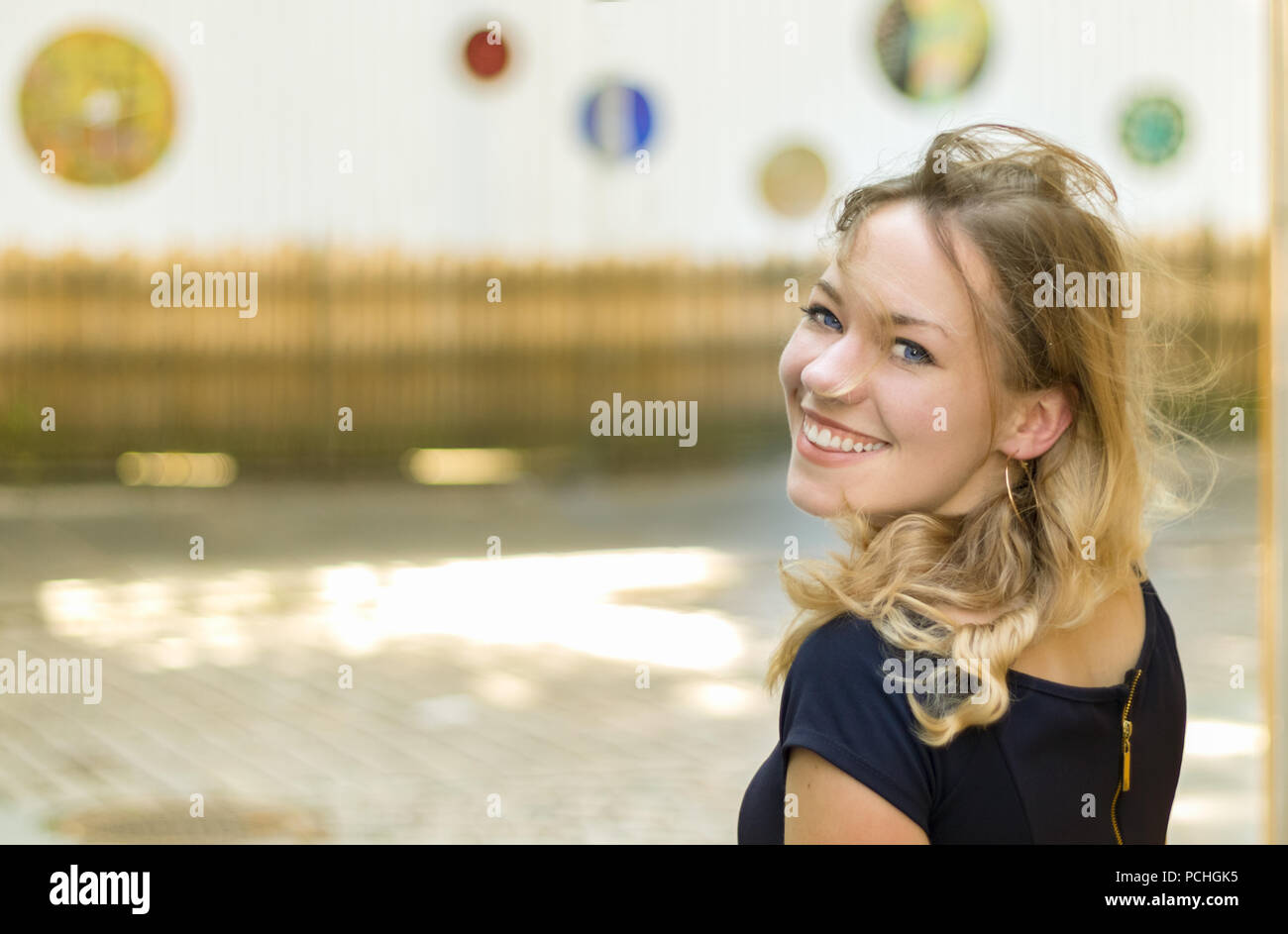 Portrait d'un jeune femme blonde aux yeux bleus, tournant la tête smiling at camera, joyeuse, à l'extérieur. Banque D'Images