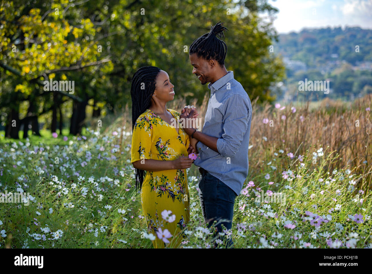 Couple holding hands dans un champ et de rire Banque D'Images