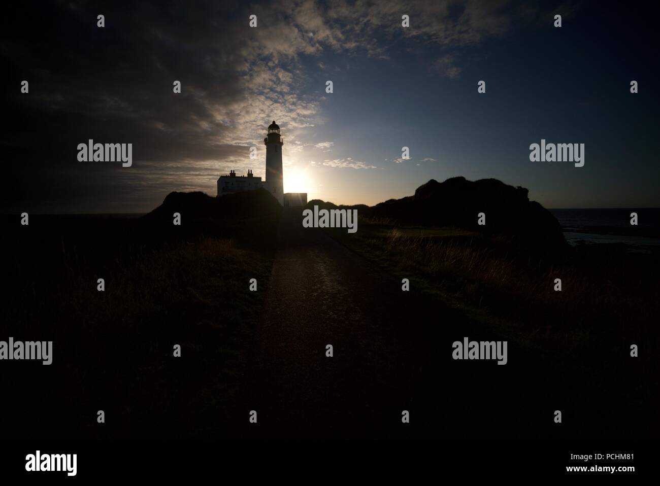 Silhouette d'un phare (Lighthouse) Turnberry le long de la Côte d'Ayrshire en regard de l'Atout Turnberry Golf, avec le coucher du soleil dans l'arrière-plan. Banque D'Images