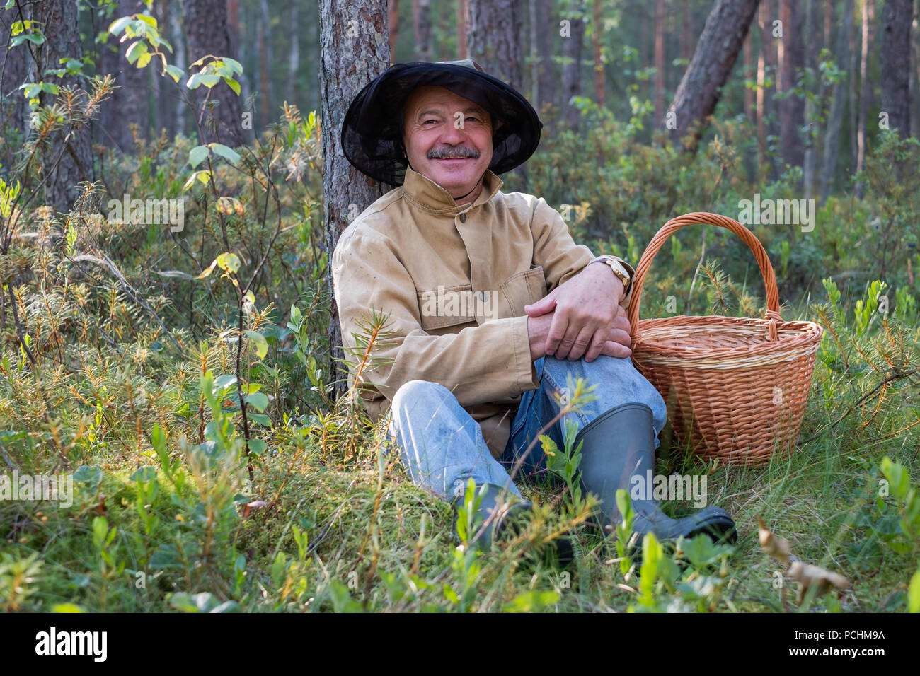 Portrait de relaxed mature homme assis dans la forêt avec panier. Banque D'Images