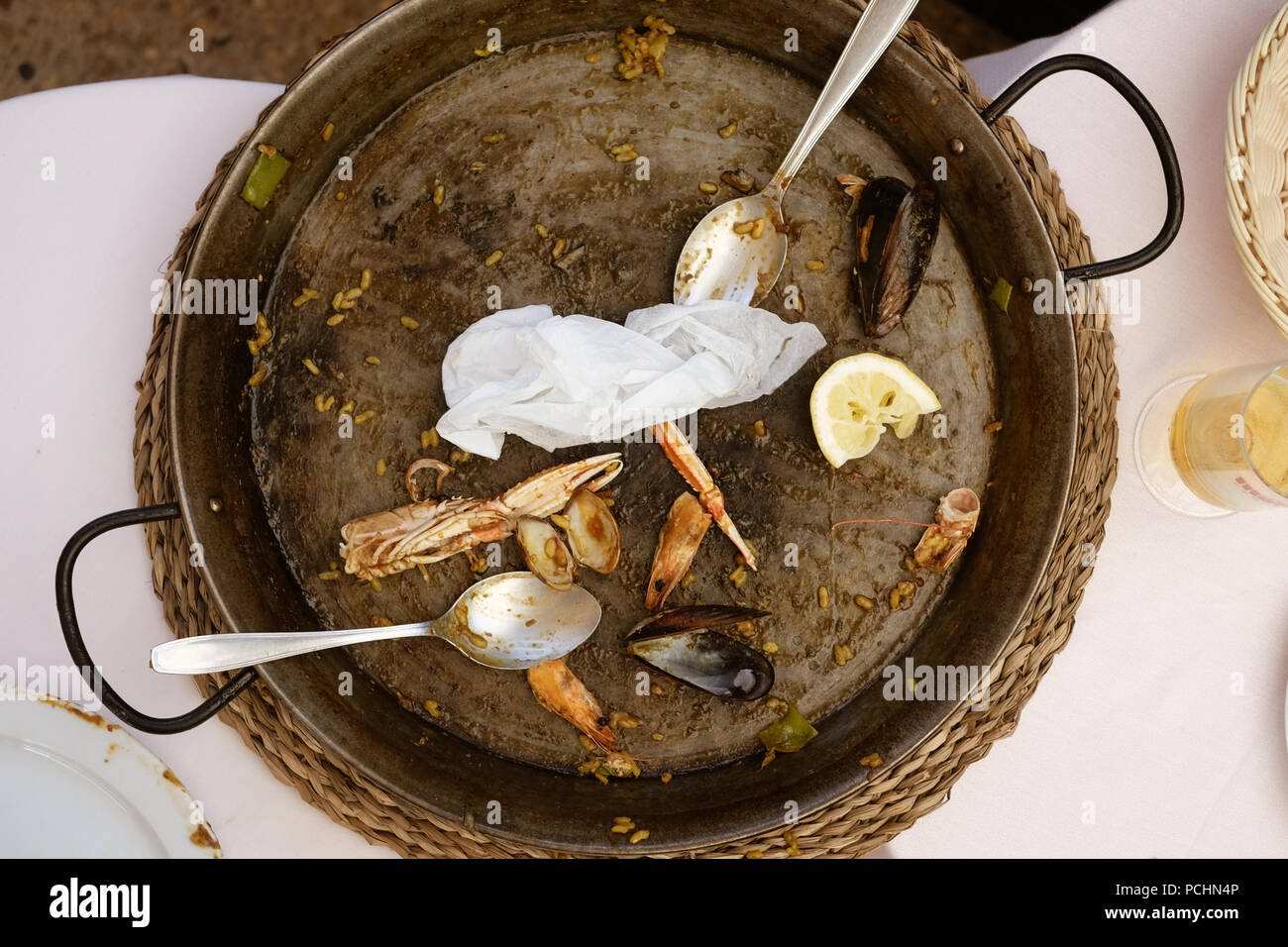 Un déjà mangé la paella poêle avec deux cuillères. Parties de crabes et de palourdes sont autour de la pose dans la vieille casserole. Banque D'Images
