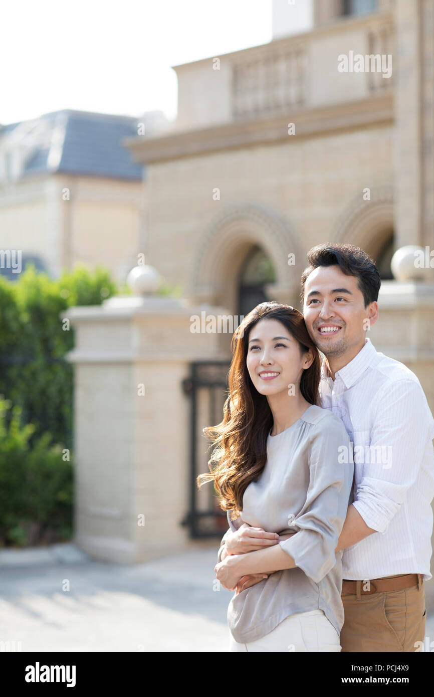 Cheerful young couple chinois en face de leur villa Banque D'Images