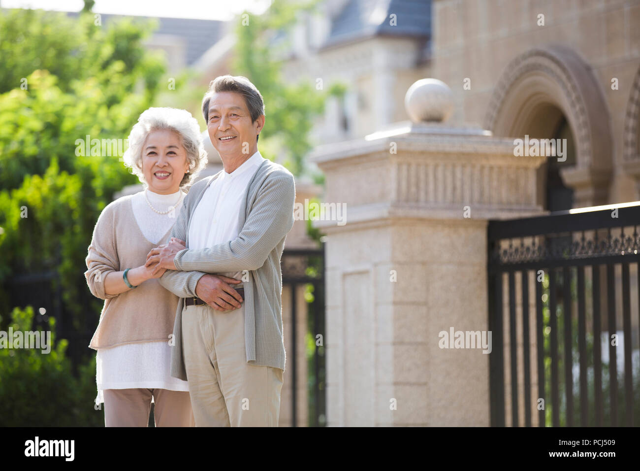 Cheerful senior couple chinois debout devant leur villa Banque D'Images