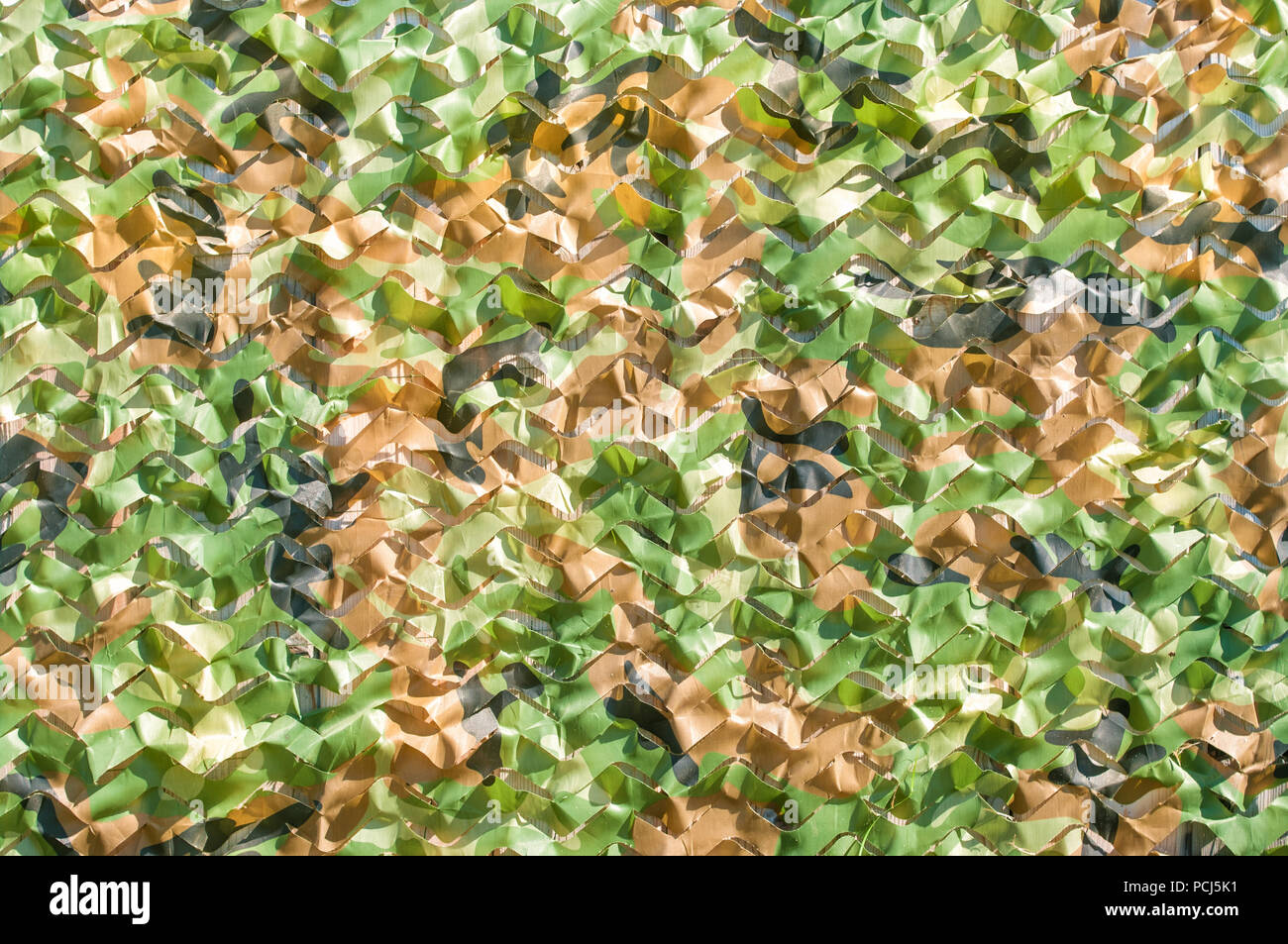Marron, vert et noir de camouflage militaire plus net sur mur extérieur en bois fond jour ensoleillé Banque D'Images