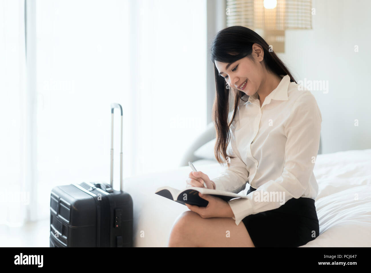 Close up of a happy Asian business woman smiling gaiement reposant à sa suite d'hôtel pendant un voyage des notes et réflexions strate Banque D'Images