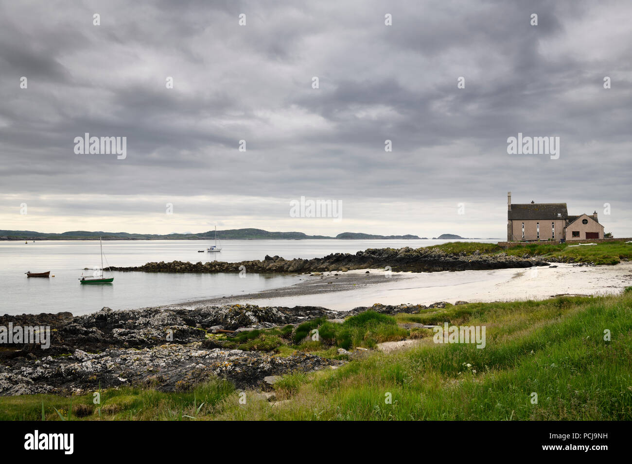 Converti à l'Église une maison sur le son d'Iona avec plage et ciel nuageux et voiliers à l'île de Iona Scotland UK Banque D'Images
