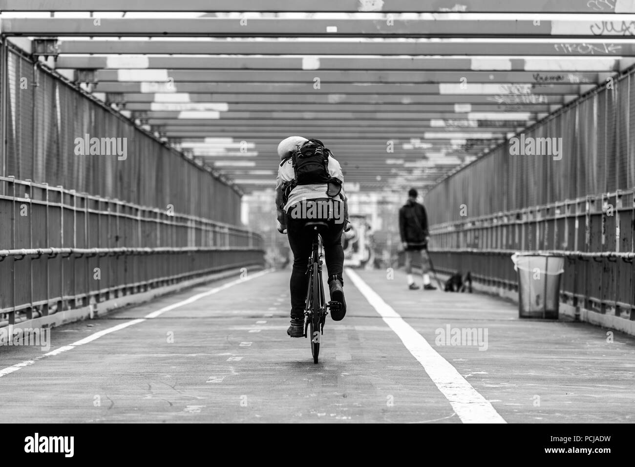 Man riding son vélo dans la voie cyclable sur le pont de Williamsburg, Brooklyn, New York City, USA. Image en noir et blanc. Banque D'Images