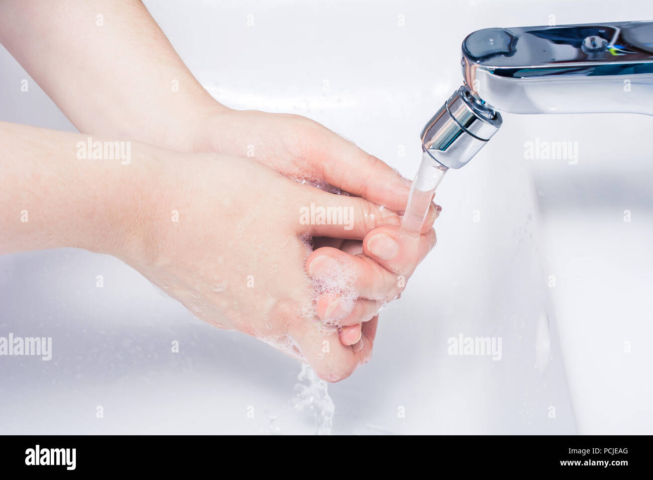 Laver les mains Savonnées sous tourné sur l'eau dans la salle de bains Banque D'Images