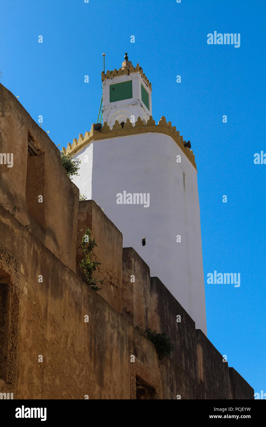 Haut de la tour de grande Mosquée de l'ancienne forteresse portugaise d'El Jadida, Maroc. Mur d'une haute clôture en premier plan. Ciel bleu. Banque D'Images