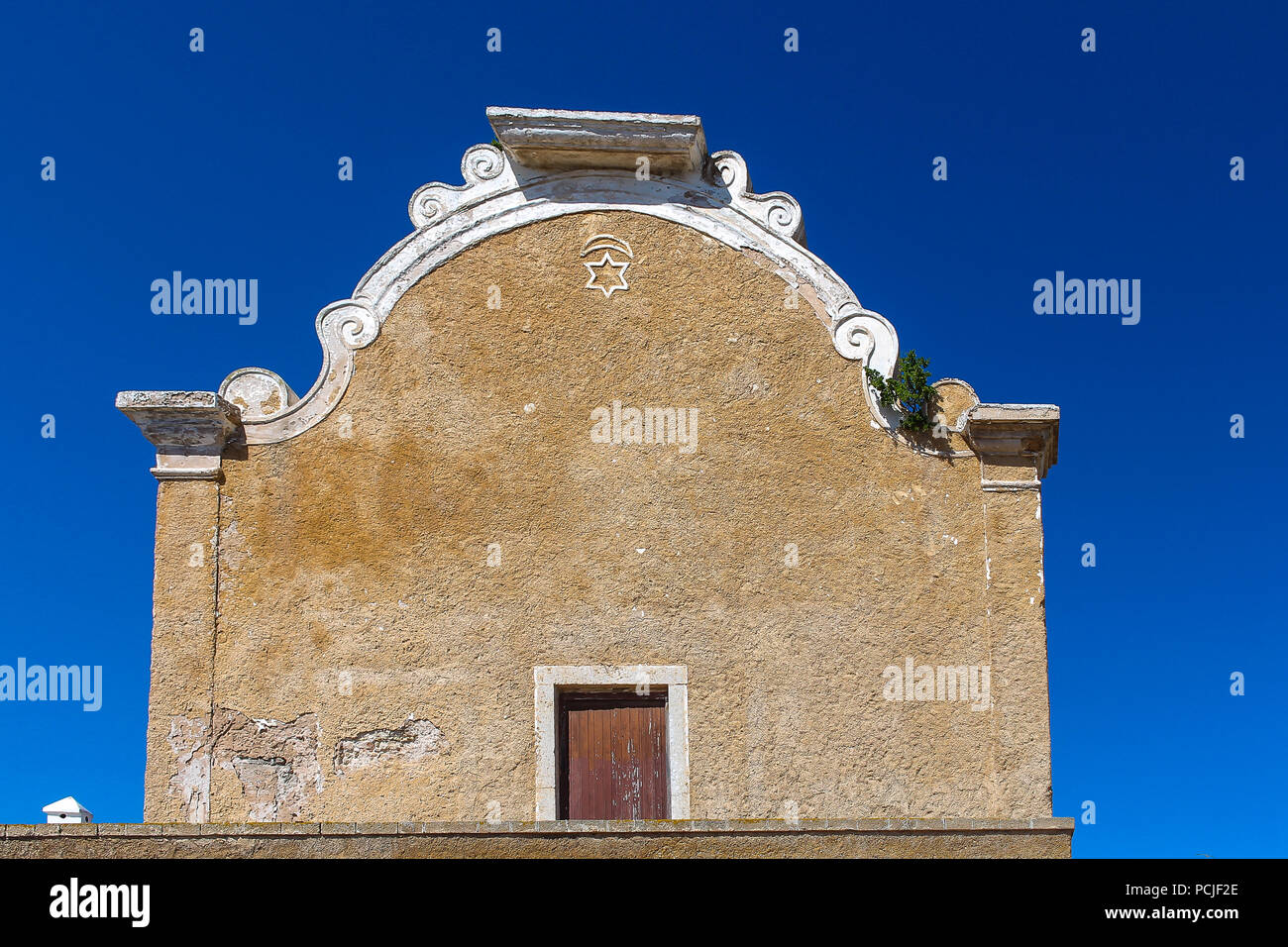 Avant de l'immeuble avec une porte et une étoile. Arche du toit. Ancienne Synagogue à El Jadida, Maroc. Ciel bleu. Banque D'Images