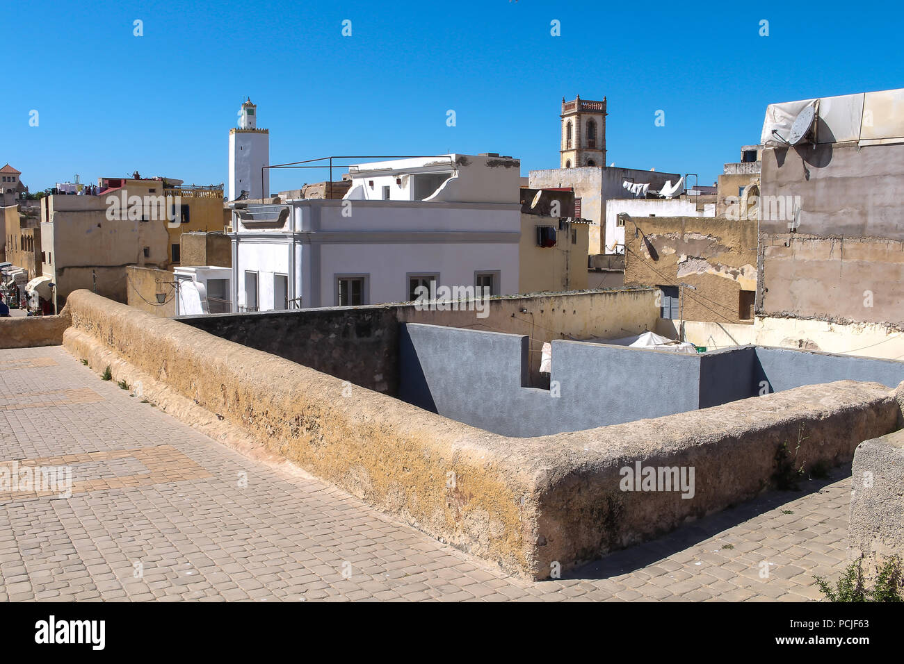 Toits et murs de l'immeuble d'habitations et d'une tour de grande mosquée de ancienne forteresse portugaise à El Jadida, Maroc. Ciel bleu. Banque D'Images