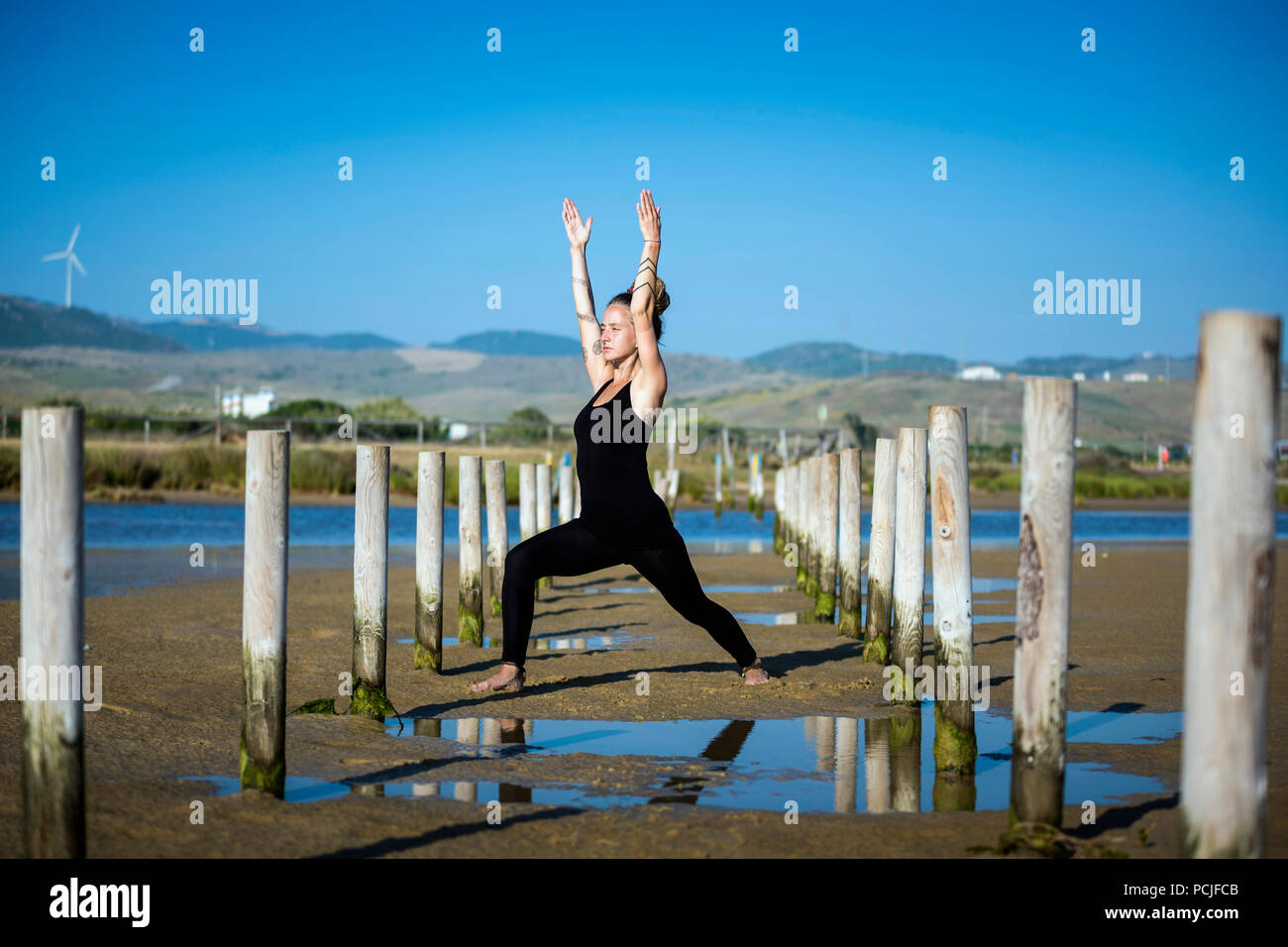 Femme debout sur la plage de Los Lances dong une fente haut yoga pose, Tarifa, Cadix, Andalousie, Espagne Banque D'Images