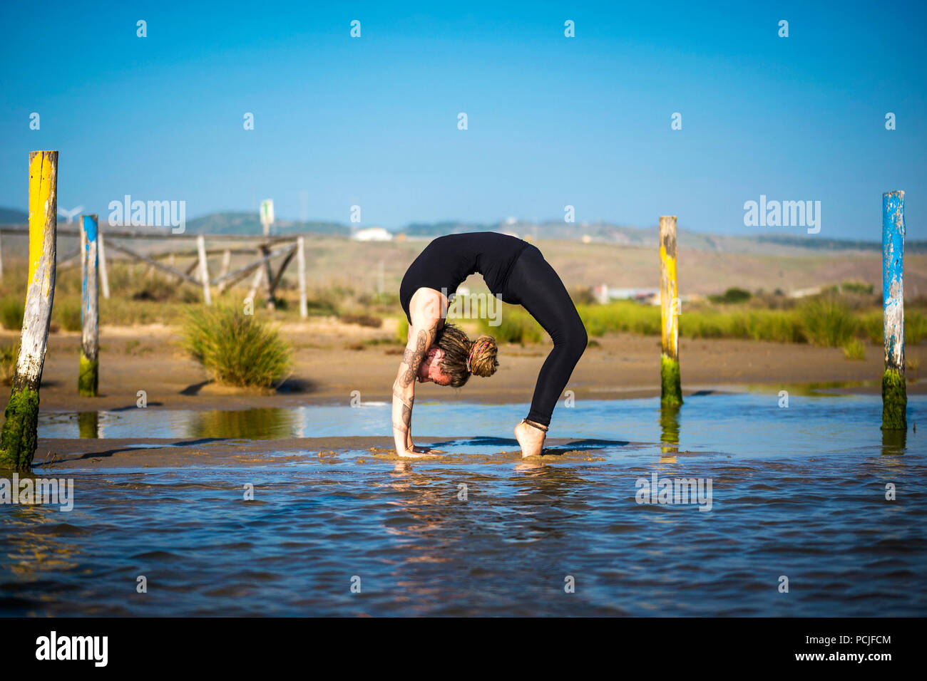Femme sur la plage de Los Lances faisant une roue yoga pose, Tarifa, Cadix, Andalousie, Espagne Banque D'Images