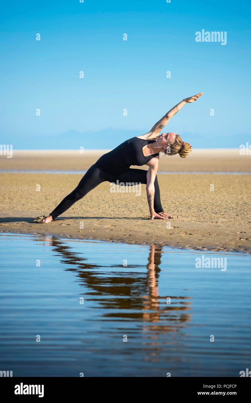 Femme sur la plage de Los Lances faisant un angle de côté yoga pose, Tarifa, Cadix, Andalousie, Espagne Banque D'Images