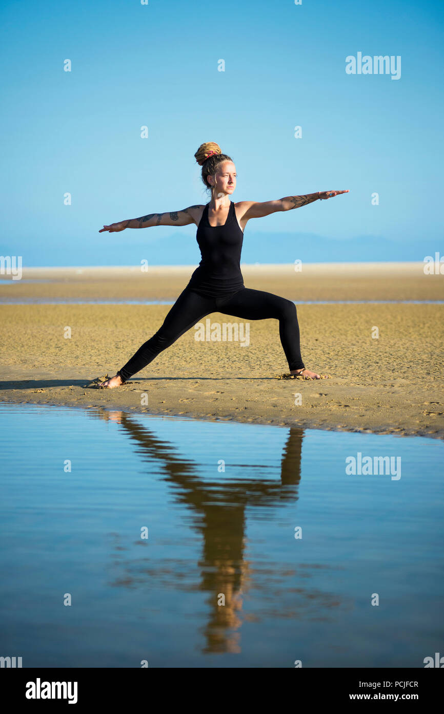 Femme sur la plage de Los Lances II guerrier faisant yoga pose, Tarifa, Cadix, Andalousie, Espagne Banque D'Images