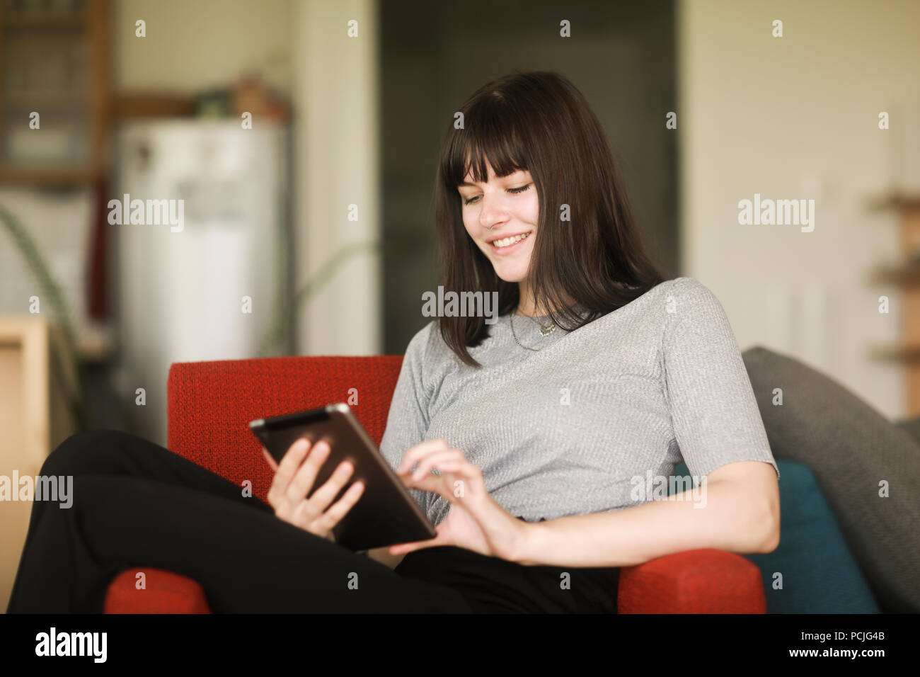 Femme assise dans un fauteuil à l'aide d'une tablette numérique Banque D'Images