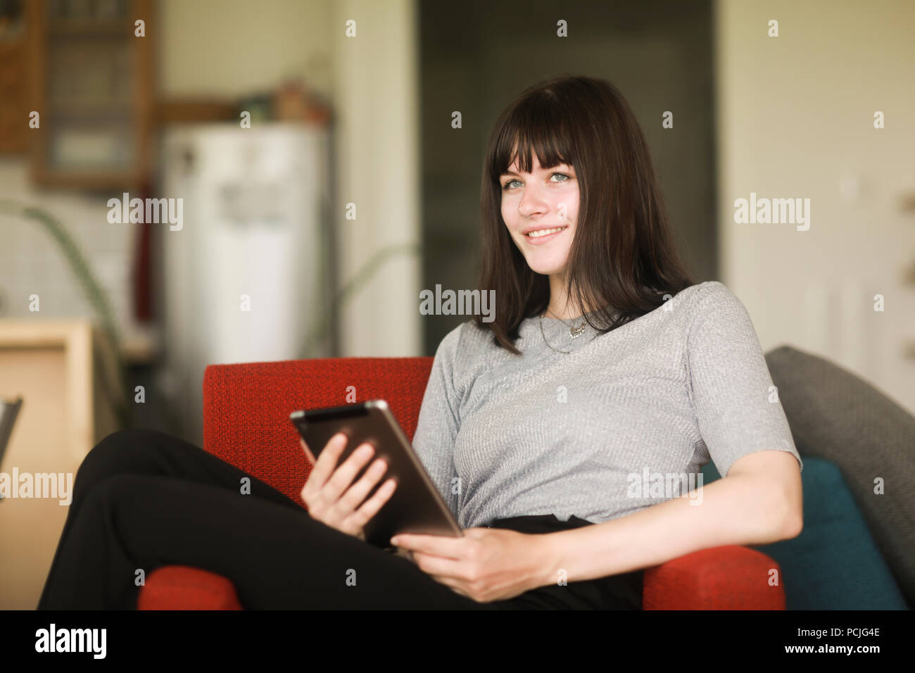 Femme assise sur un fauteuil à l'aide d'une tablette numérique Banque D'Images