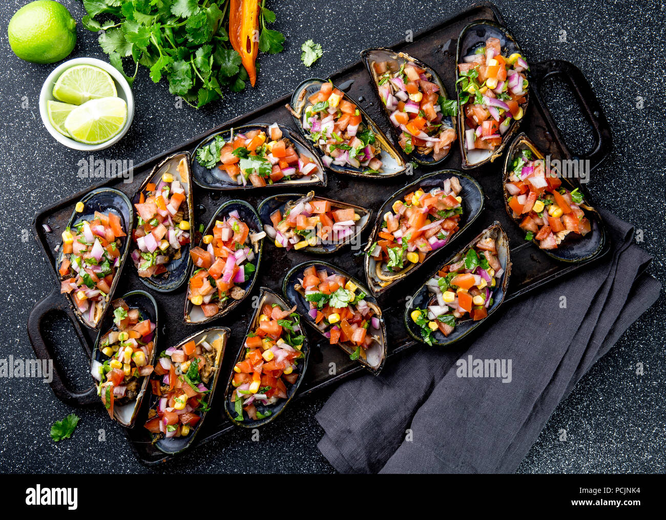 La nourriture péruvienne. Choros a la chalaca. Gros moules, choros zapatos assaisonné de purple oignon, les tomates, le maïs et le citron. Vue de dessus, fond noir. Plat péruvien traditionnel Banque D'Images