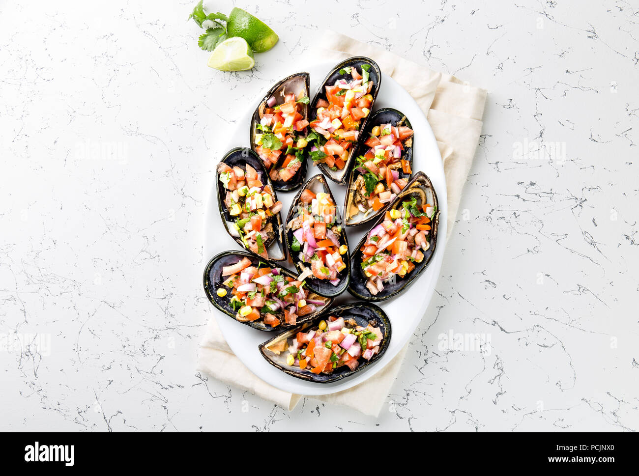 La nourriture péruvienne. Choros a la chalaca. Gros moules, choros zapatos assaisonné de purple oignon, les tomates, le maïs et le citron. Vue de dessus, fond blanc. Plat péruvien traditionnel Banque D'Images
