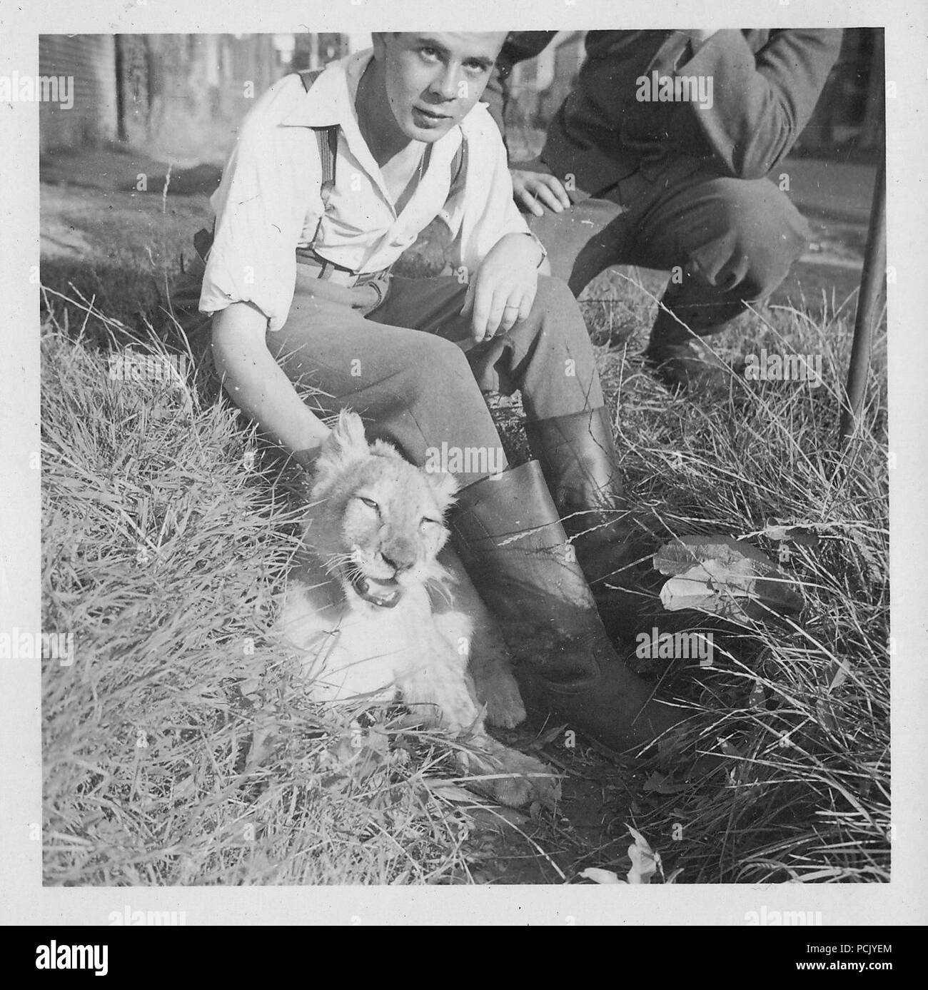 Image à partir d'un album de photos relatives à II. Gruppe, Jagdgeschwader 3 : Un garçon français joue avec 'Simba', le lion cub mascotte de II. Gruppe, Jagdgeschwader 3, dans une ville française à l'été 1940. Banque D'Images