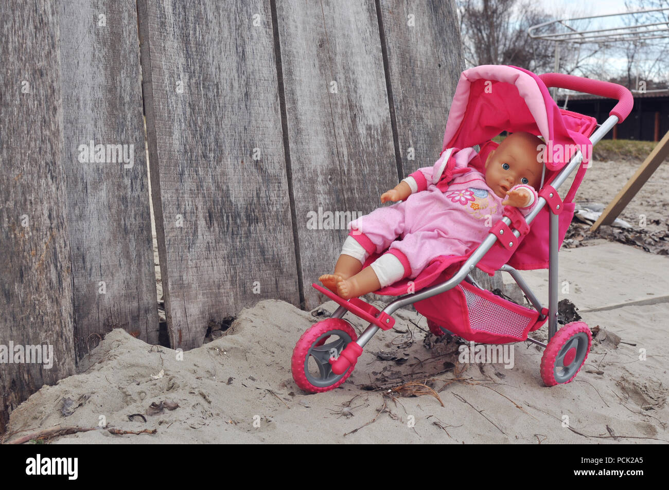 Poussette jouet bébé fille abandonnée à l'extérieur sur jour d'automne froid Banque D'Images