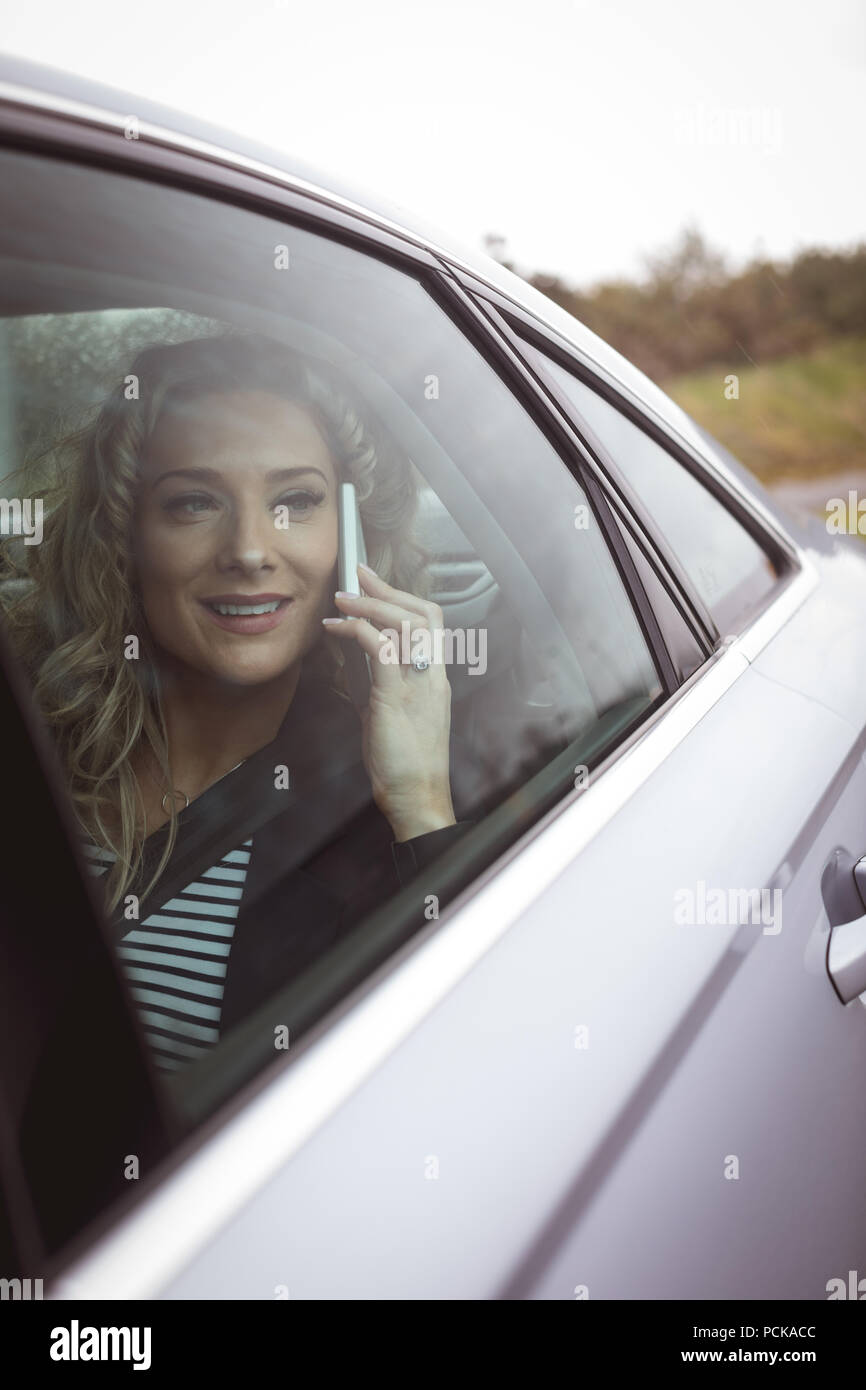 Businesswoman talking on the phone dans le siège arrière de la voiture Banque D'Images