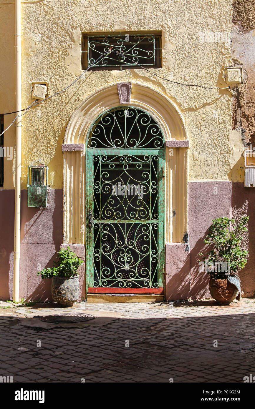 Yellów et rose couleur de la façade d'une maison avec une porte avec arc et vert et treillis. Dans l'ancienne ville forteresse portugaise à El Jadida, Maroc Banque D'Images