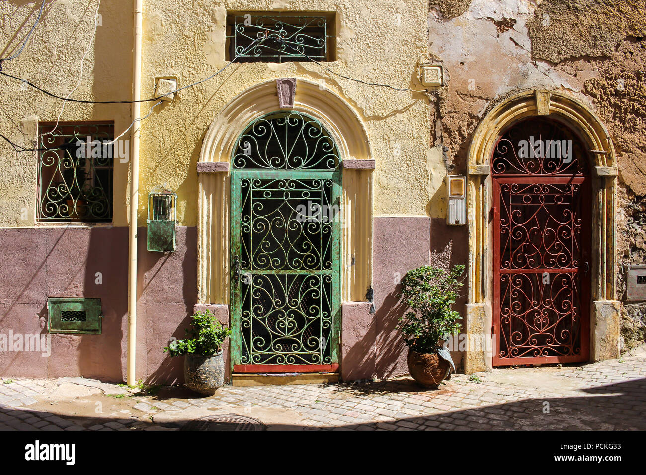 Yellów et rose couleur de la façade d'une vieille maison avec 2 portes avec et archs et treillis vert et rouge. Dans l'ancienne ville forteresse en portugais Banque D'Images