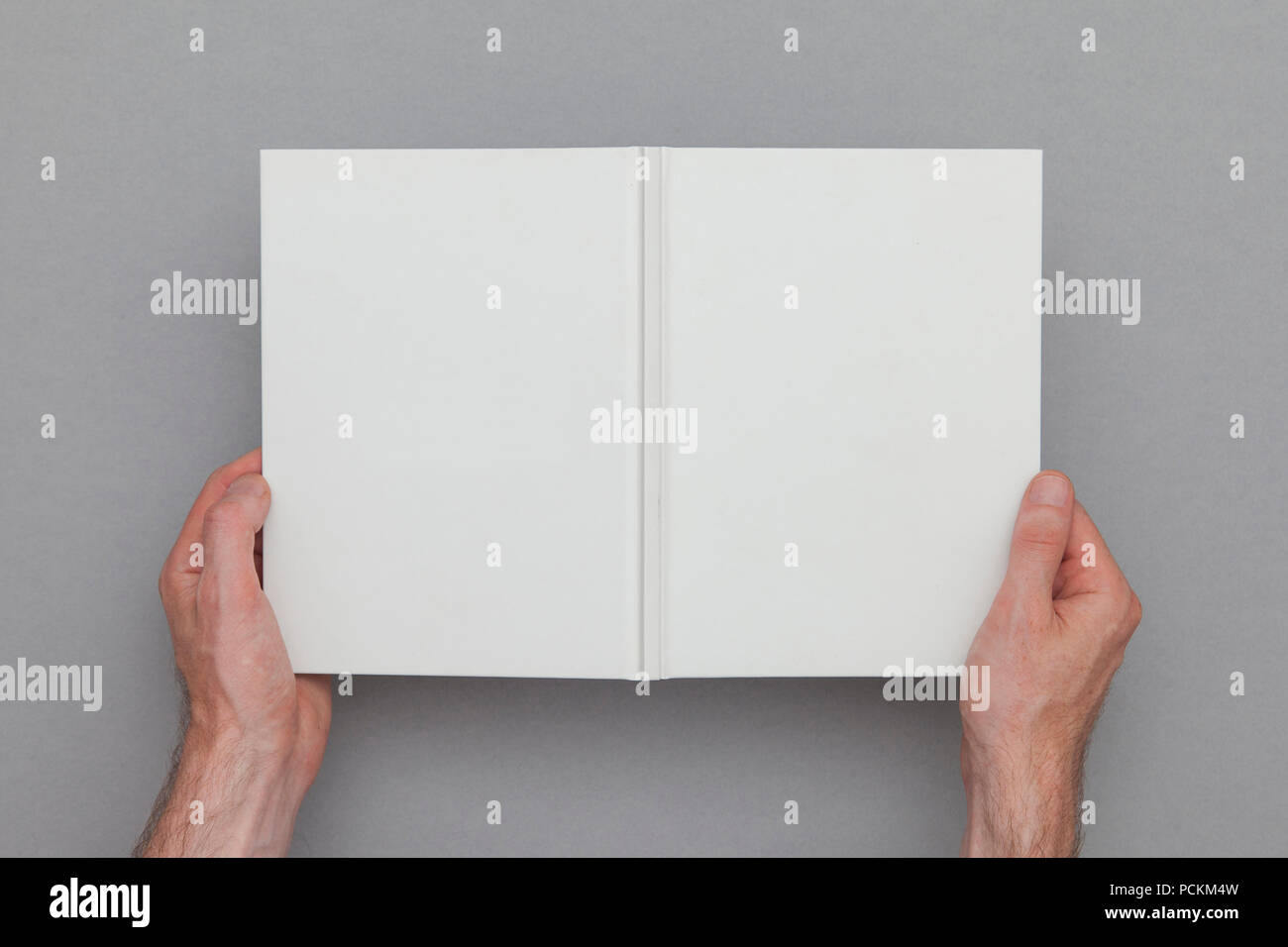 Homme main tenant un livre ouvert montrant les couvertures de livre. La maquette du livre modèle. Banque D'Images