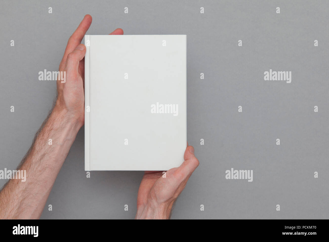 Homme main tenant un livre fermé montrant la couverture du livre. La maquette du livre modèle. Banque D'Images