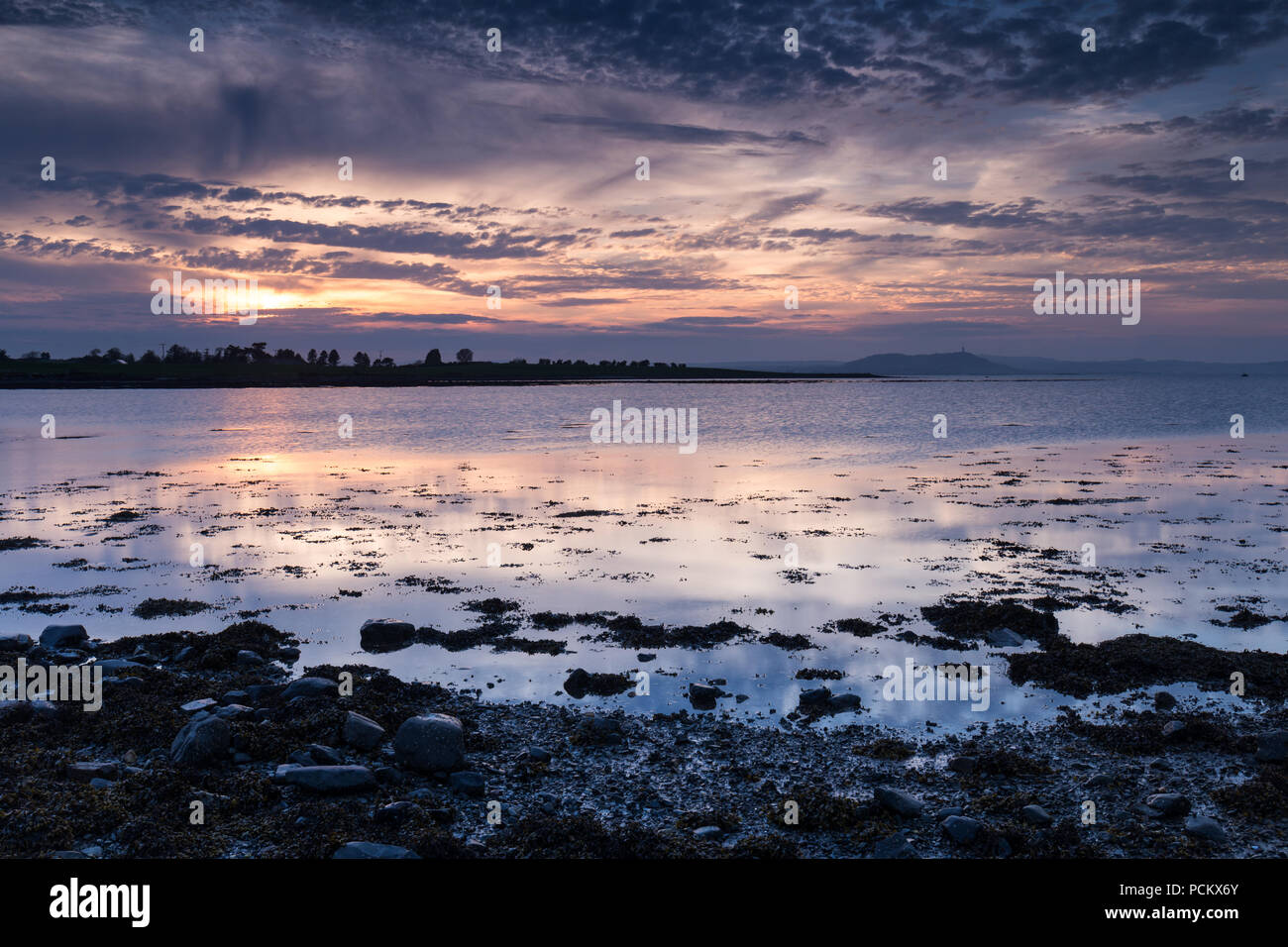 Skyscape coucher de soleil spectaculaire sur Strangford Lough avec vue sur monument local Scrabo Tower à distance. Banque D'Images