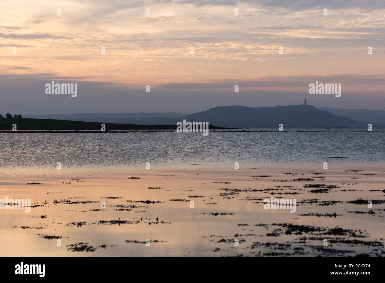 Coucher de soleil sur le Strangford Lough avec Scrabo Tower sur la colline parlementaire à distance, comté de Down, Irlande Banque D'Images