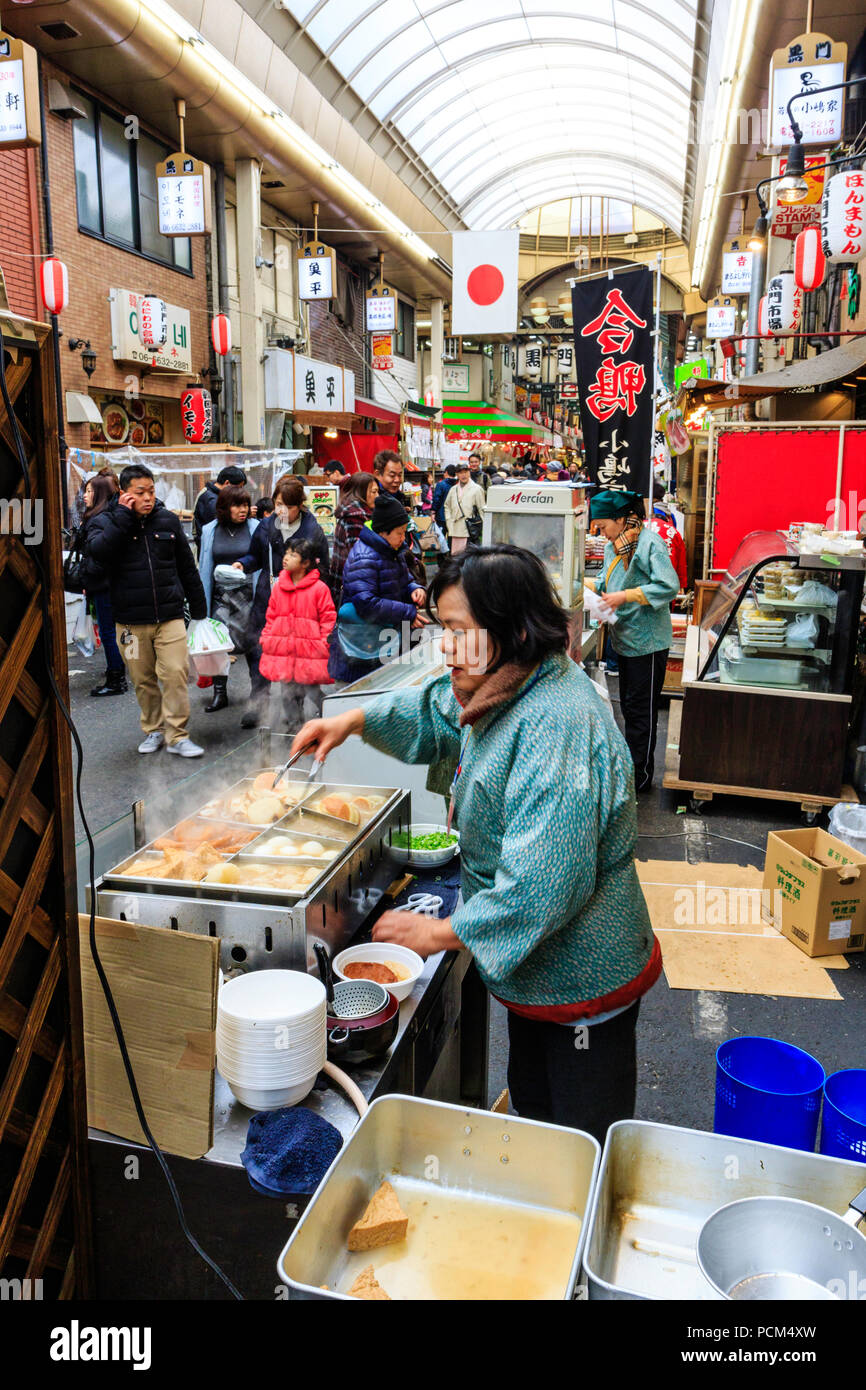 Kuromon Ichiba, Osaka's kitchen marché alimentaire. Voir l'arcade le long avec cabine en premier plan la vente de oden, hiver type de nourriture. Marché intérieur de monde. Banque D'Images