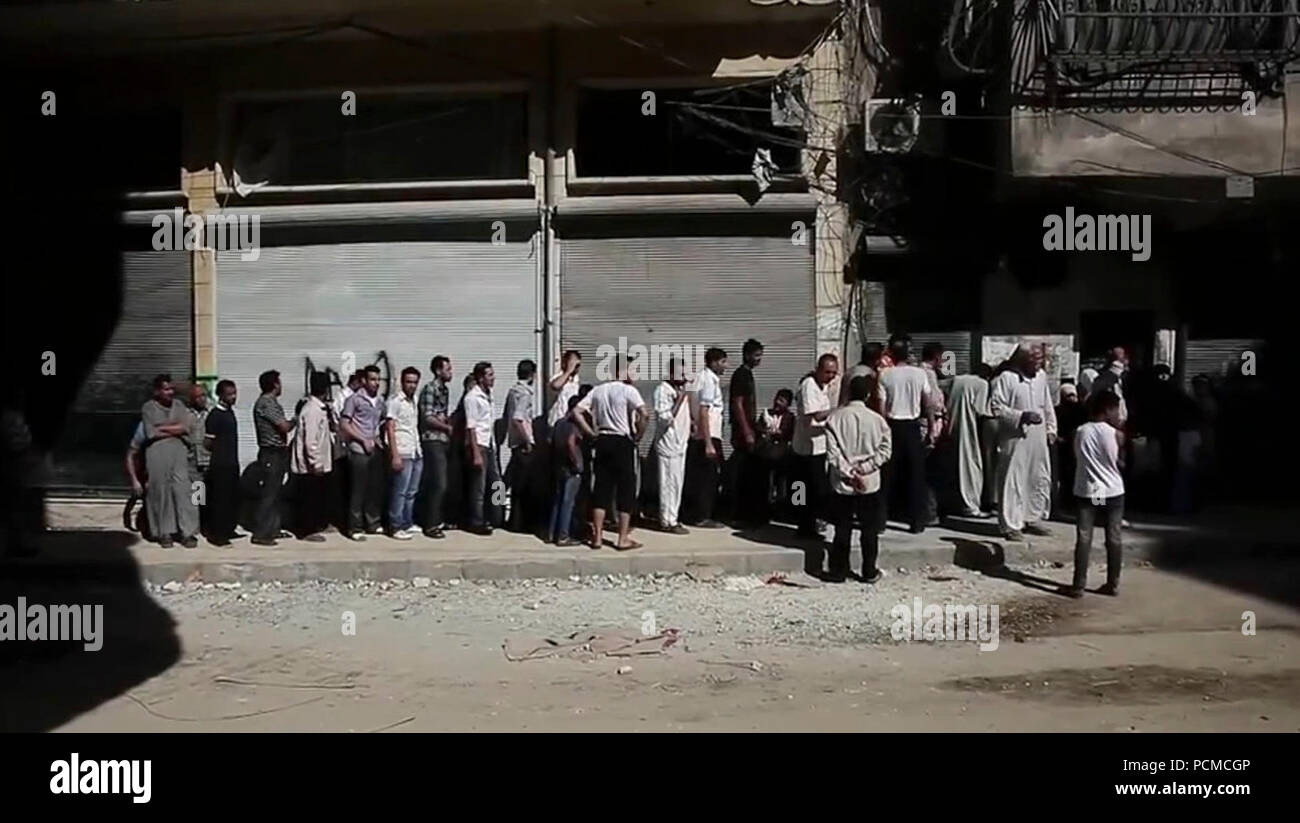Aleppians en attente dans une ligne de pain au cours de la guerre civile en Syrie. Banque D'Images