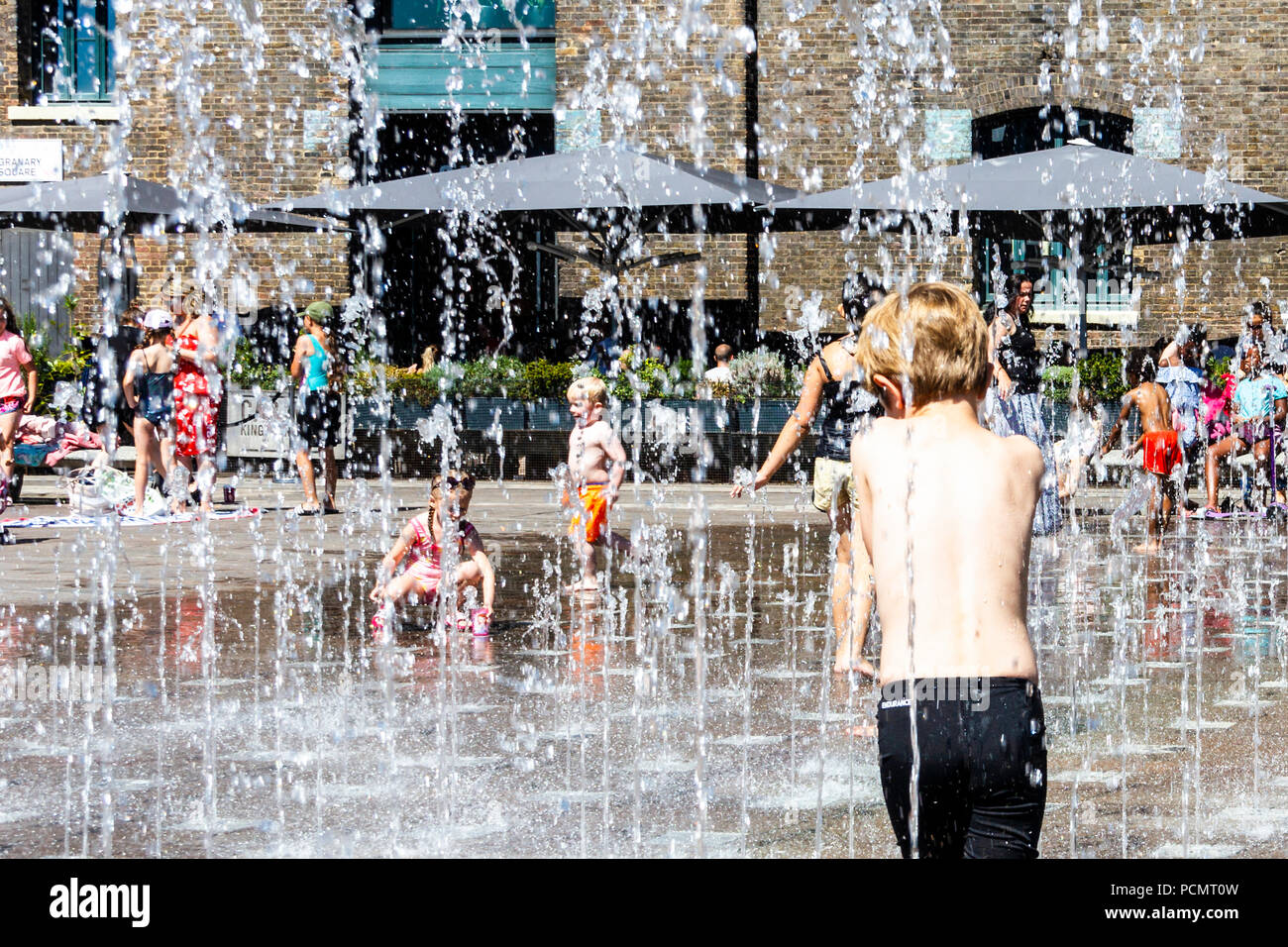 Les familles et les enfants se rafraîchissent dans les fontaines de Granary Square tandis que les températures montent, King's Cross, Londres, Royaume-Uni Banque D'Images