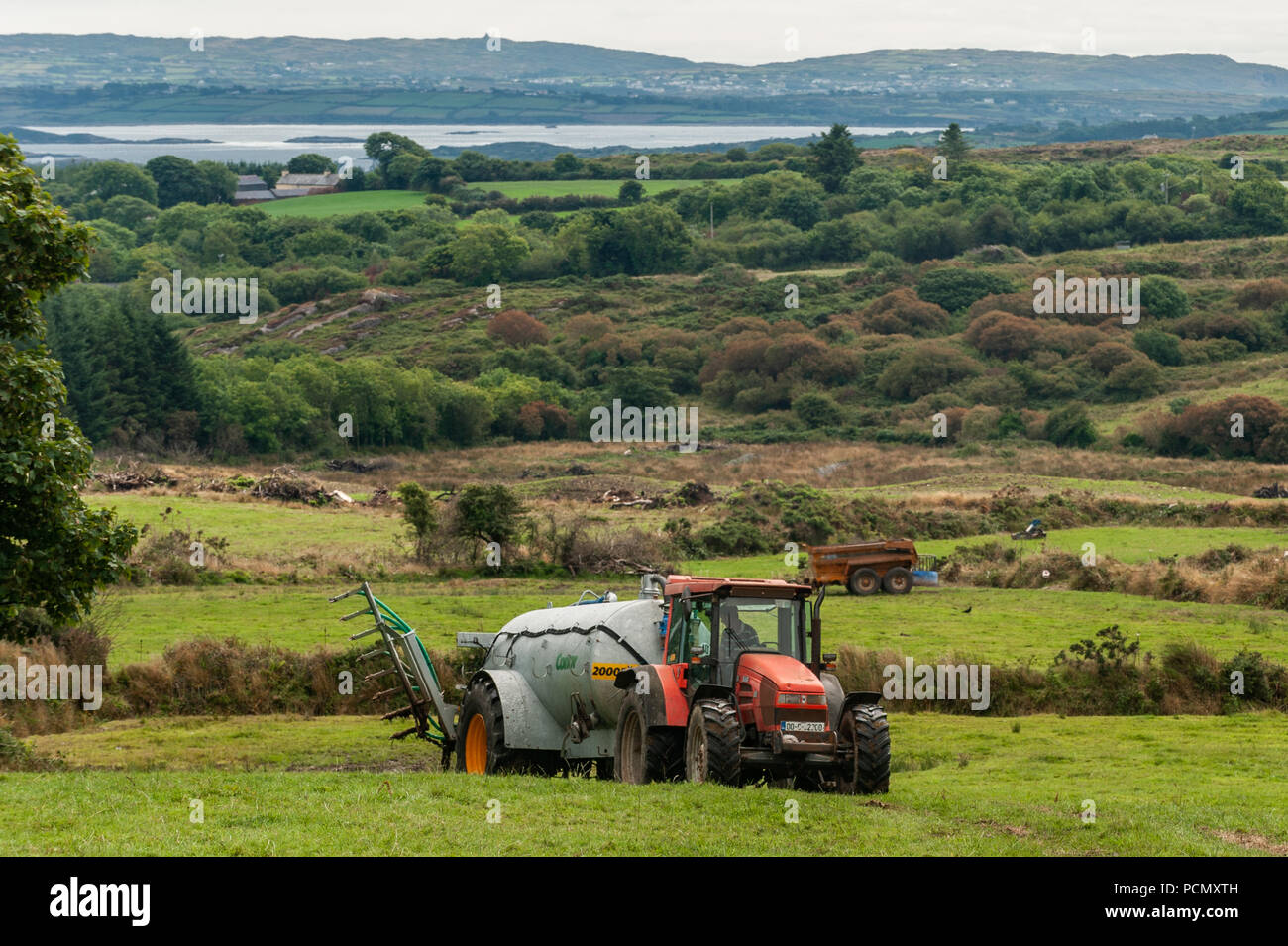 Ballydehob, West Cork, Irlande. 3e août 2018. Avec Roaring Water Bay à l'arrière-plan, un agriculteur basé Durrus lisier pulvérisations sur son domaine sous un ciel couvert mais chaude journée. La canicule est de retour ce week-end, en pluie au début de la semaine prochaine. Credit : Andy Gibson/Alamy Live News. Banque D'Images