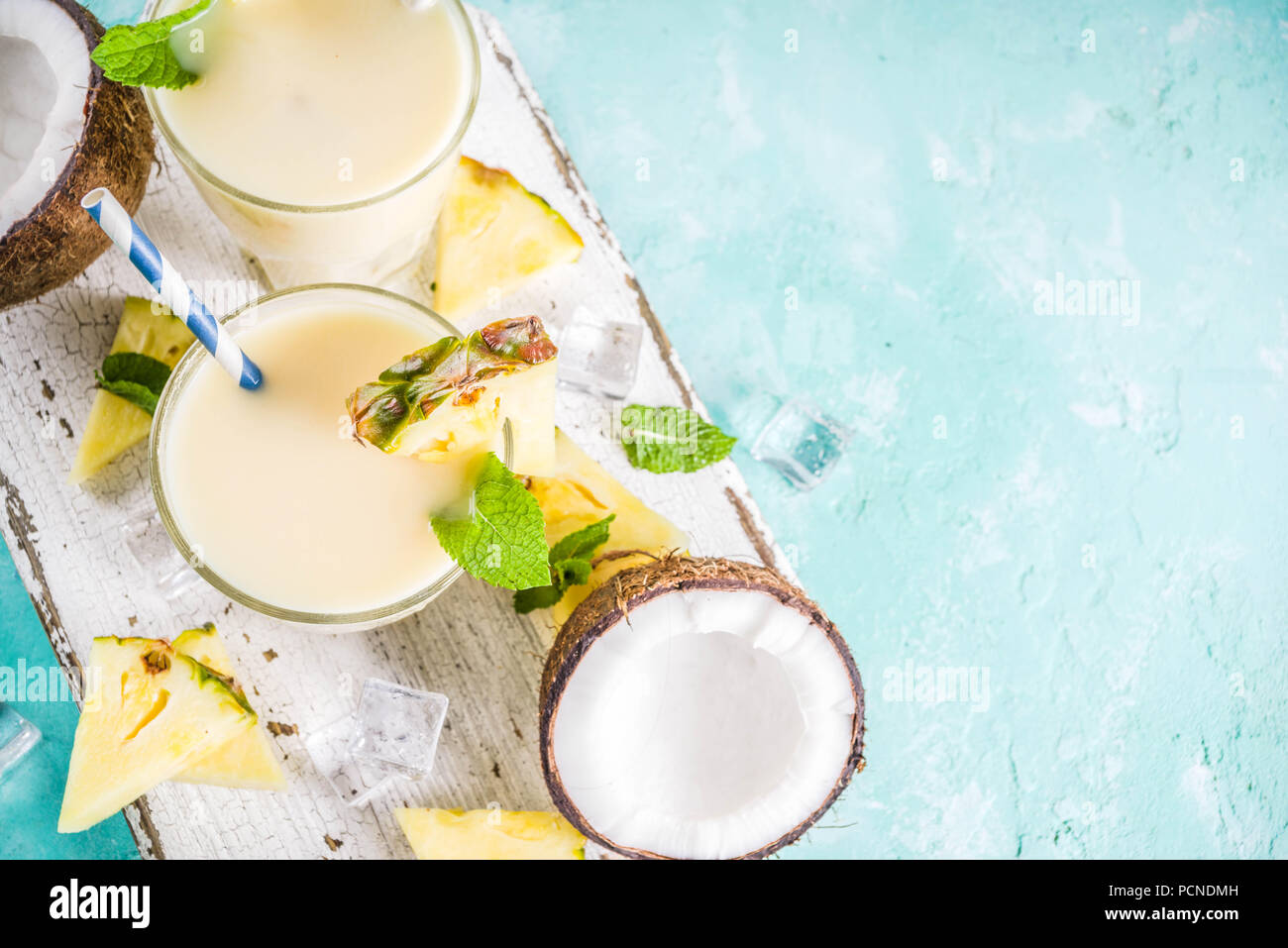 Boisson d'été rafraîchissante, de pina colada cocktail, sur un fond bleu clair, avec des morceaux d'ananas, noix de coco, de glace et de feuilles de menthe, copy space Banque D'Images