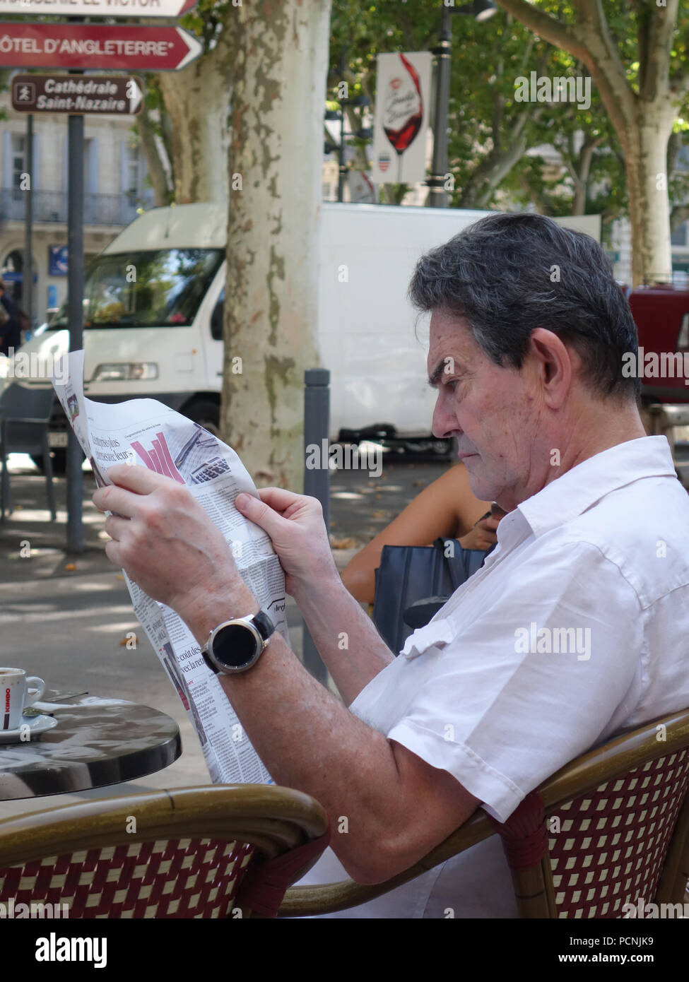 L'homme assis à l'extérieur tout en relaxant french street cafe reading a newspaper Banque D'Images