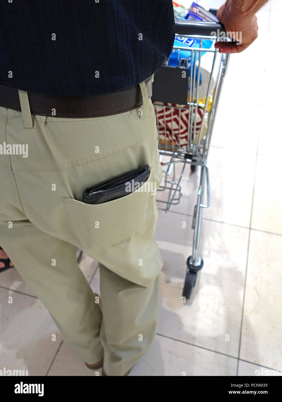 Old man shopping in supermarket avec son porte-monnaie sur l'affichage complet sortant de sa poche arrière prêt pour un pickpocket Banque D'Images