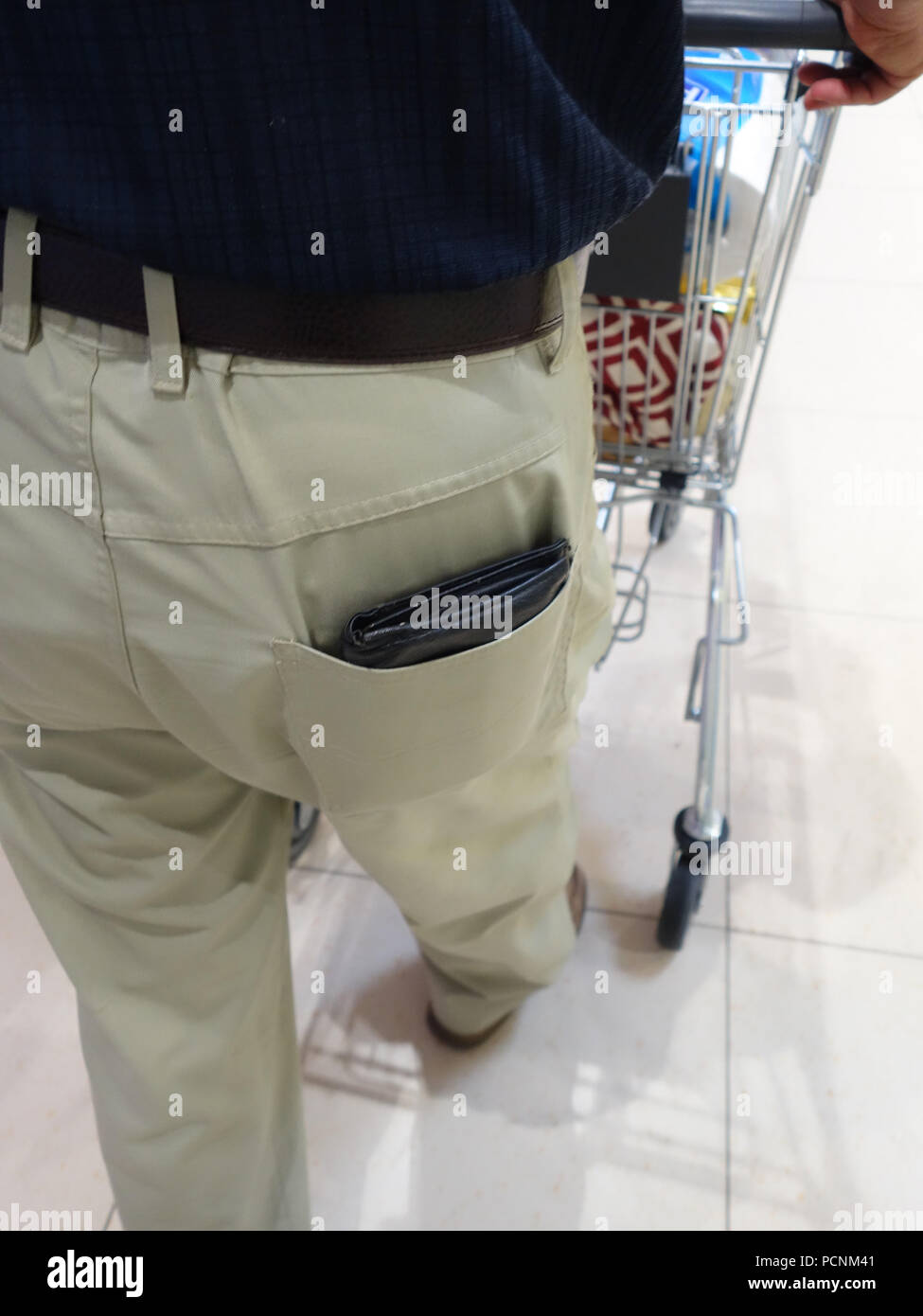 Old man shopping in supermarket avec son porte-monnaie sur l'affichage complet sortant de sa poche arrière prêt pour un pickpocket Banque D'Images