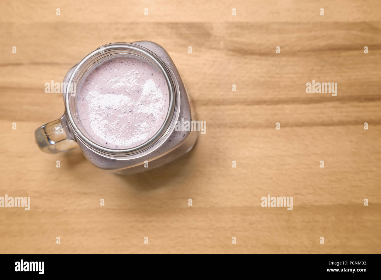 Smoothie aux petits fruits dans un pot Mason sur une planche à découper en bois. Banque D'Images Smoothie aux petits fruits dans un pot Mason sur une planche à découper en bois. Banque D'Images
