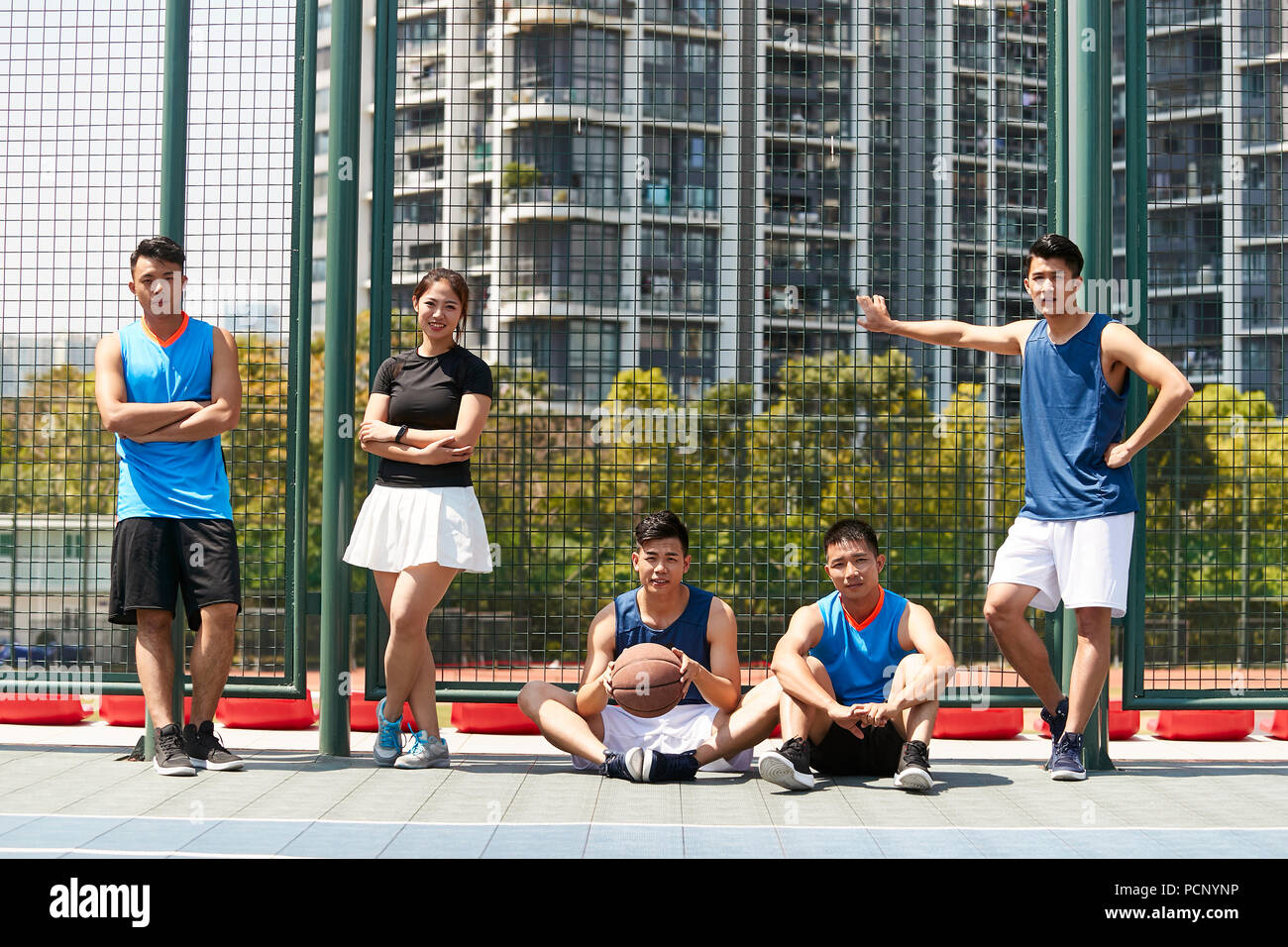 Cinq jeunes adultes asiatiques de détente sur un terrain de basket en plein air après l'exercice. Banque D'Images