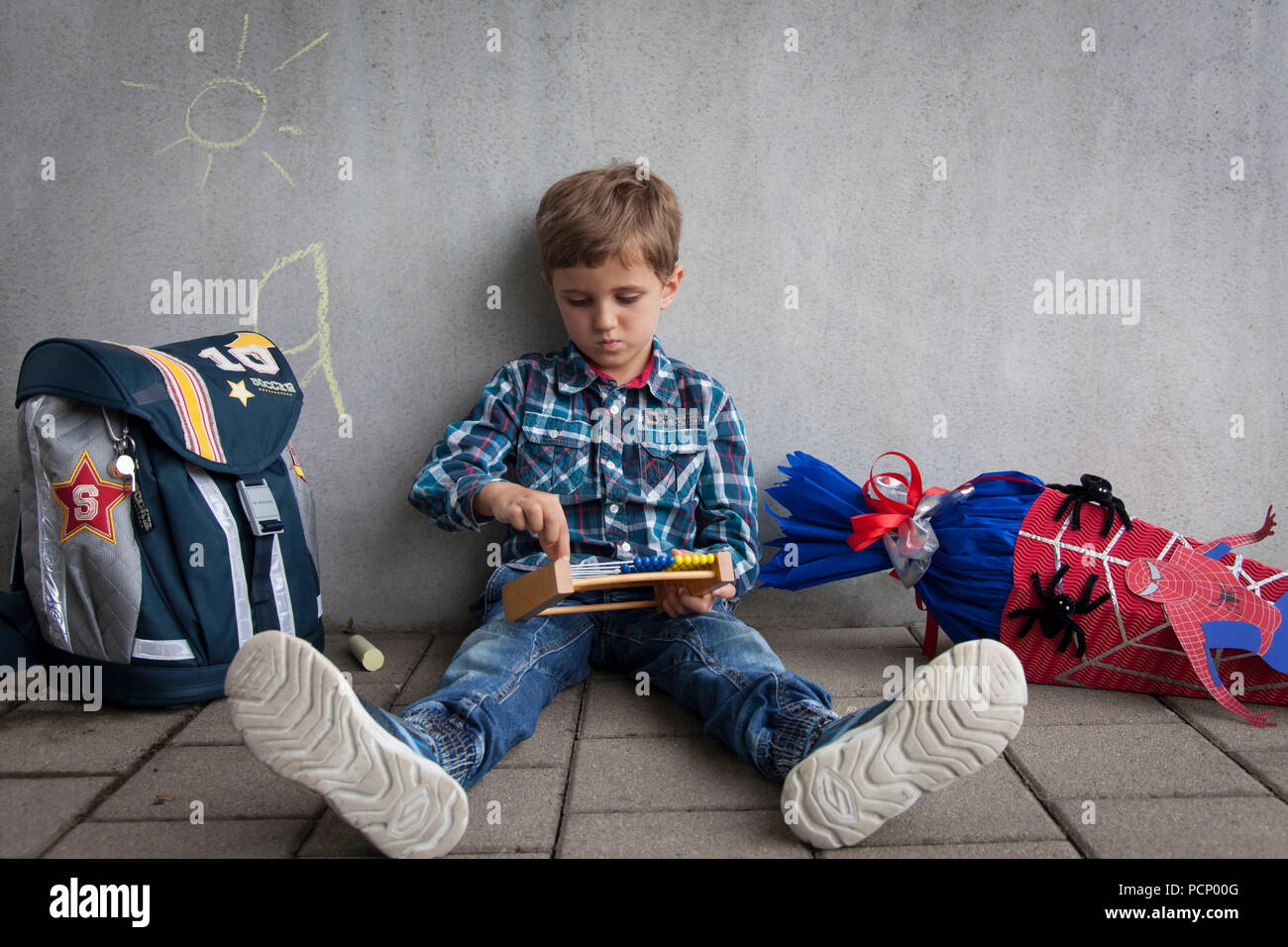 Boy with school cone et sac d'école assis sur le plancher Banque D'Images