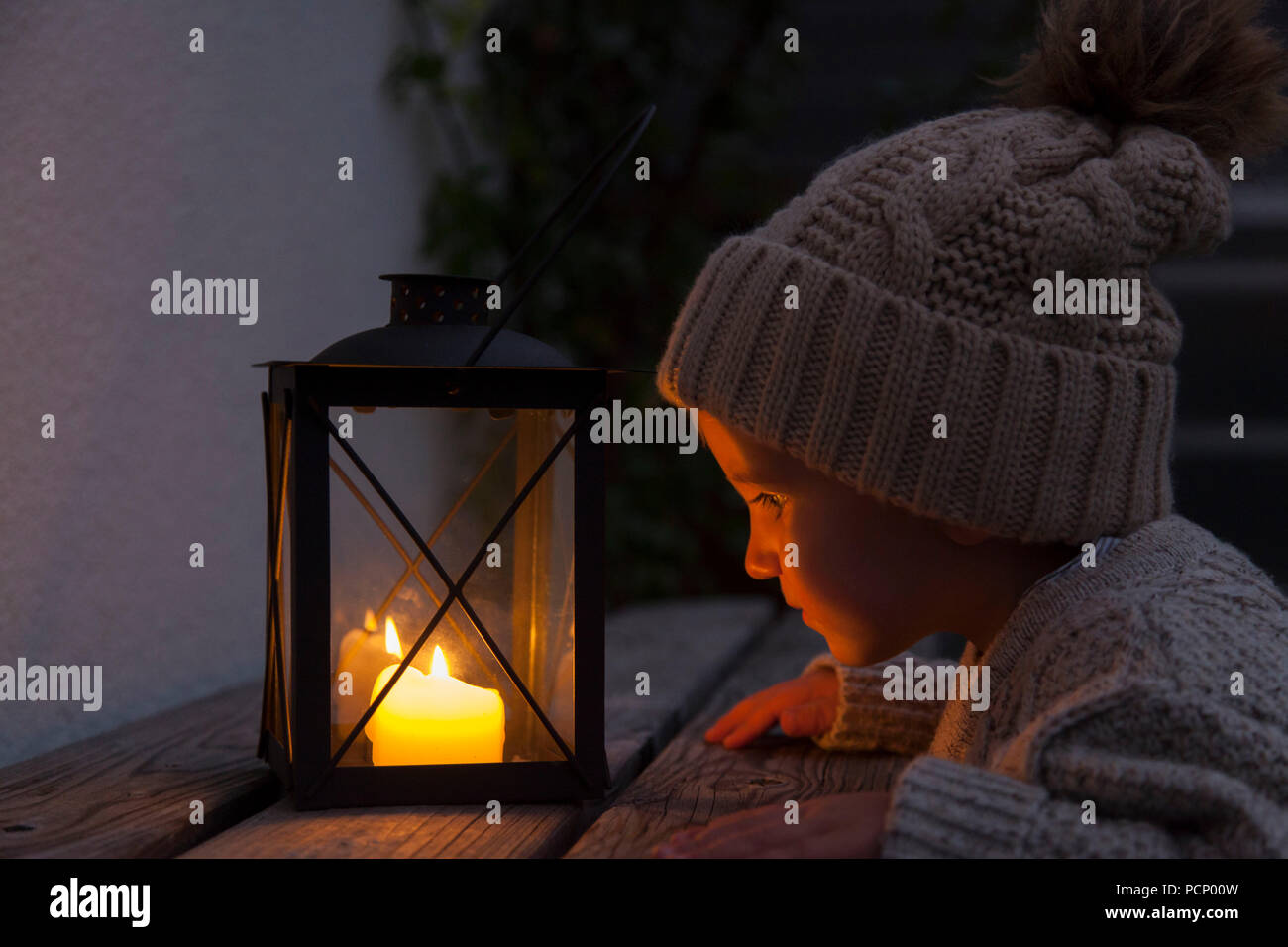 Petit garçon face à des bougies d'une lanterne Banque D'Images