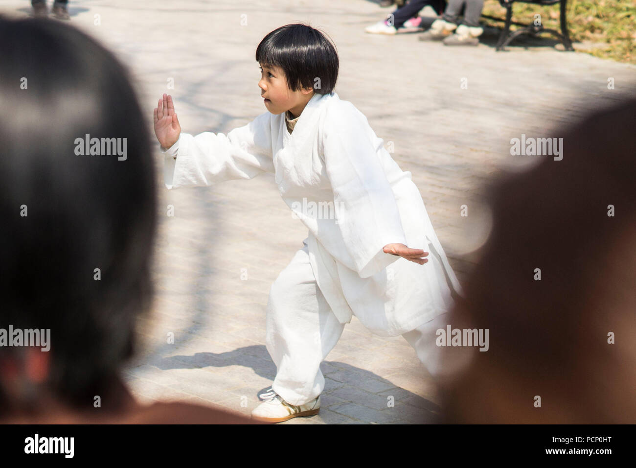 Le Qigong pratiquant un garçon au milieu d'un groupe de personnes à Nanjing, Chine Banque D'Images