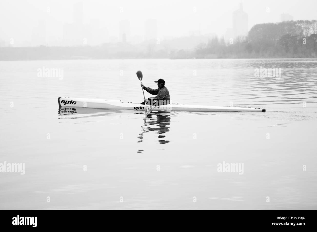 Un homme est une pataugeoire avec son kayak dans un lac à Nanjing, Chine Banque D'Images